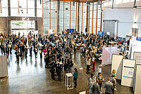 Participants stand in the entrance hall of the Estoril Convention Centre during the industry exhibition